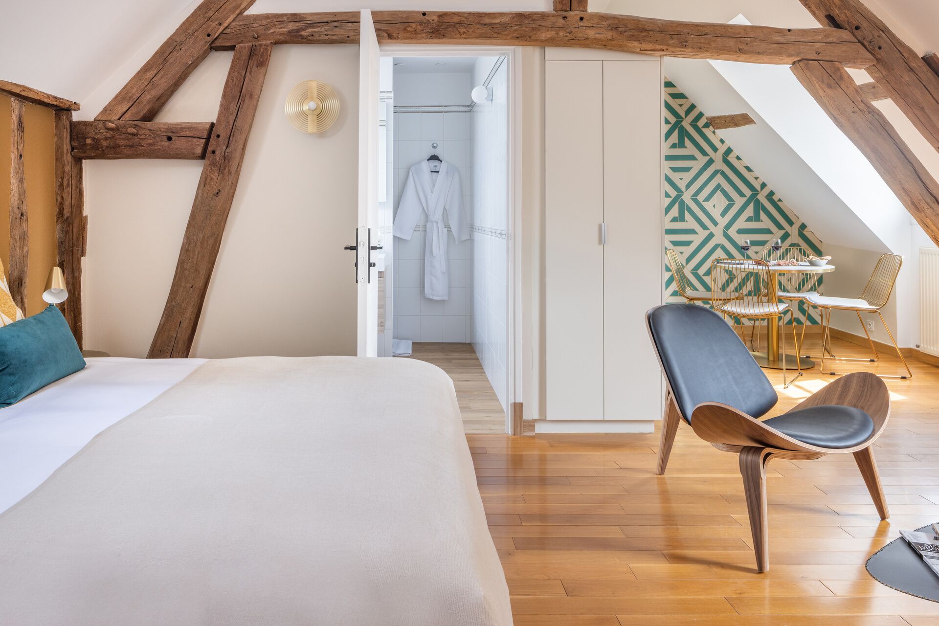 Un dormitorio con una cama grande, techo de madera, baño con ducha y comedor con mesa y sillas.