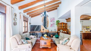 A living room with two beige sofas, a wooden coffee table, a TV, and a fireplace. - Cubo's Villa El Sauce de Coin / Private pool / BBQ / Air conditioning / Free Wi-Fi (Coín)