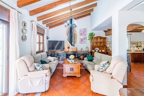 Ein Wohnzimmer mit zwei beigefarbenen Sofas, einem Holztisch, einem Fernseher und einem Kamin.