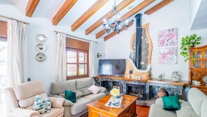 A living room with a sofa, armchairs, a television, a fireplace, and decorative wall art. - Cubo's Villa El Sauce de Coin / Private pool / BBQ / Air conditioning / Free Wi-Fi (Coín)