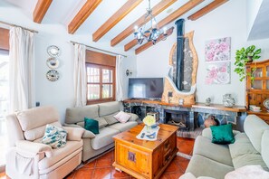 Ein Wohnzimmer mit Sofa, Sesseln, einem Fernseher, einem Kamin und Wandbildern.