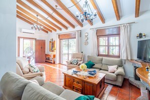 Amplia sala de estar con techo de madera, televisor y comedor con mesa y sillas.