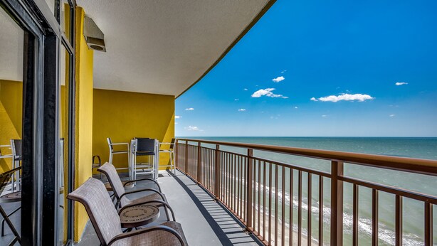 Un balcone con vista sull'oceano, pareti gialle e una ringhiera.