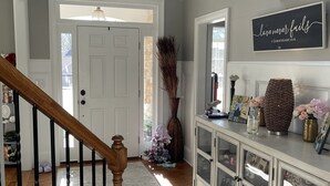 A hallway with a wooden staircase, a white door, and a cabinet with glass doors.