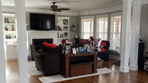 A spacious living room with hardwood floors, a fireplace, a TV, and a comfortable seating area.