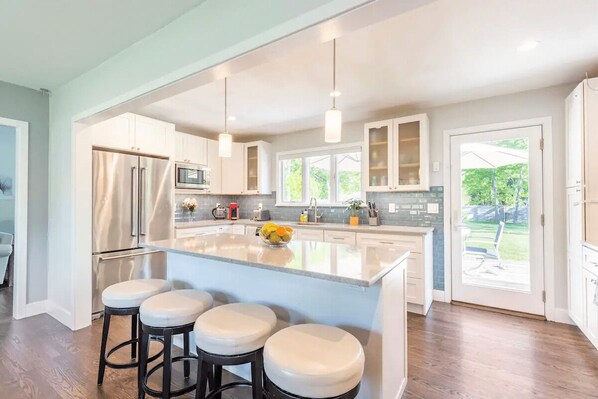 A modern kitchen with a large island, stainless steel appliances, and a view to the outdoors.