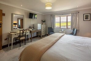 A bedroom with a bed, a desk, a chair, a dresser, a television, and a window with curtains. - Beacons View B&B (Brecon)