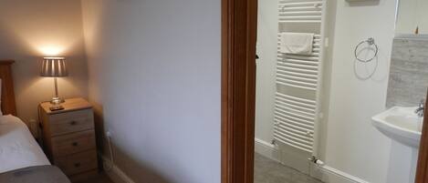 Quarto com cama, luminária de cabeceira e mesa de apoio.