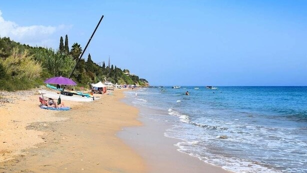 Una playa con arena, algunas embarcaciones y sombrillas.