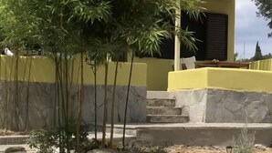 Una casa con fachada amarilla y tejado de tejas rojas, y un pequeño balcón.
