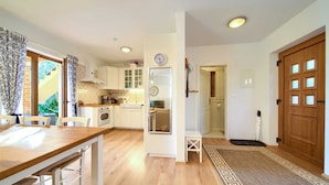 A modern kitchen with white cabinets, a wooden dining table, and a view of the outdoors. - Villa Rustika with a swimming pool and beautiful Seaview (Sužan (Krk))