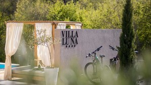 A villa named "Villa Luna" with a pool, a pergola with white curtains, and bicycles parked against a wall. - Villa Luna with heated swimming pool & E-bikes (Županje (Krk))