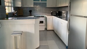 A kitchen with white cabinets, a stove, a microwave, and a refrigerator.