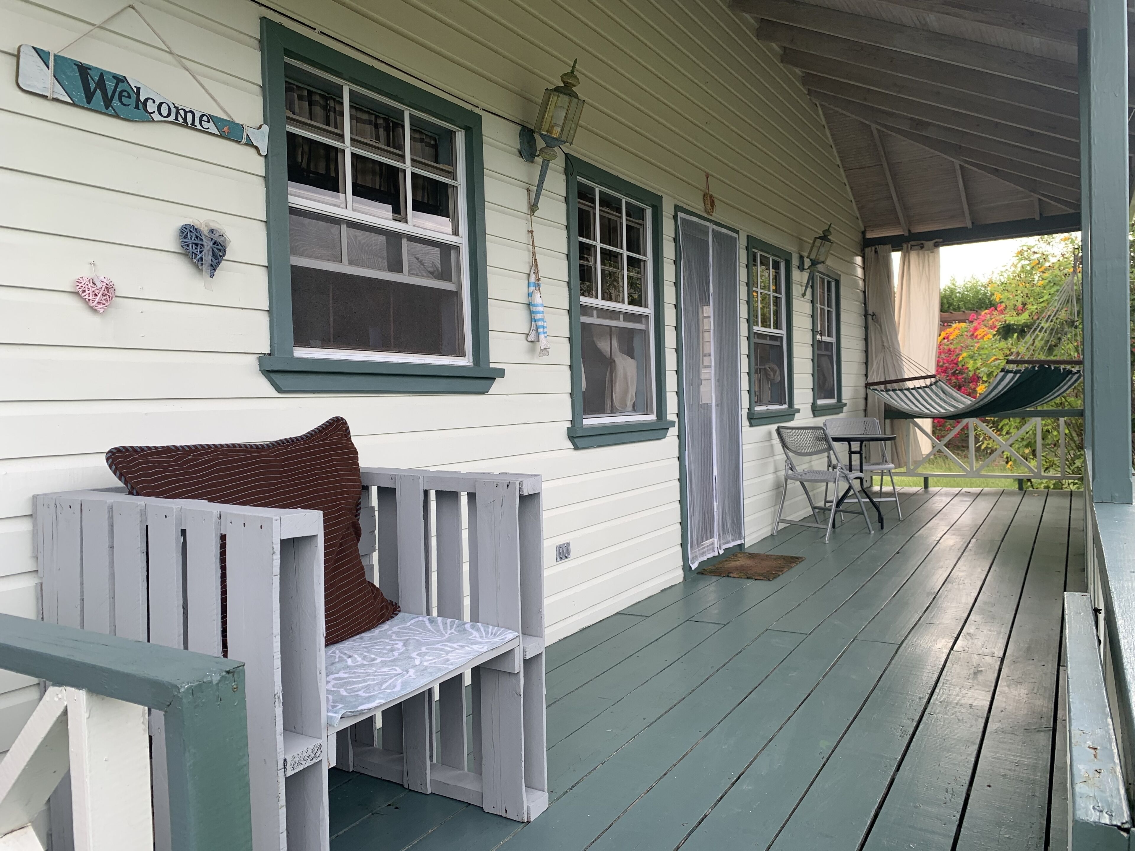 Une véranda avec un banc, un hamac et une table avec des chaises.