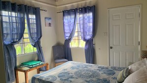 A bedroom with a bed, a chair, a table, and curtains.