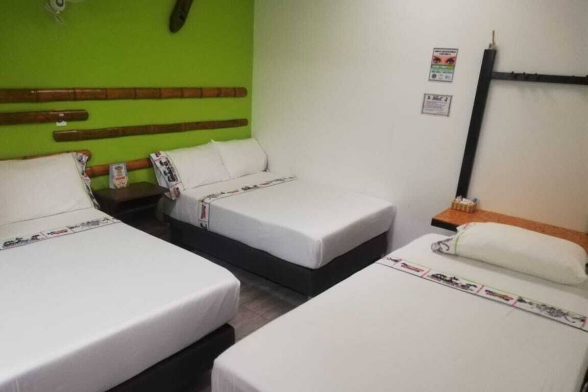 Ein Hotelzimmer mit zwei Betten, einer grünen Wand und einem Holzkopfende.