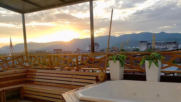 Een dakterras met een jacuzzi, houten zitplaatsen en potplanten.