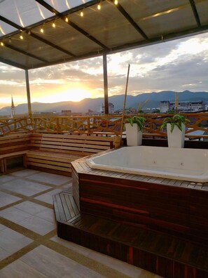 Eine Dachterrasse mit Whirlpool, Holzmöbeln und Topfpflanzen.