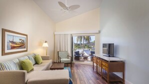 Ein Hotelzimmer mit Sofa, Sessel, Fernseher und einem Balkon mit Blick.