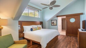 Ein Schlafzimmer mit Bett, Deckenventilator, Fenster, Tür und Fernseher.