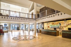 A spacious lobby with a reception desk, a large decorative floor design, and a view of the outdoors.