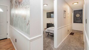 En hall med en stor karta på den vänstra väggen, en säng i mitten och en darttavla på den högra väggen.