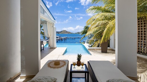 A poolside lounge with a view of the sea, a pineapple, and a straw hat on the table. - Waterfront Villa-Amazing View-Pool-Sea-Location#1 (Pointe Pirouette)
