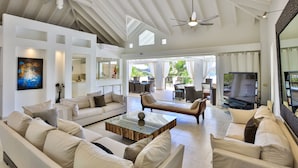 A spacious living area with a high ceiling, a ceiling fan, and a large flat-screen TV. - Waterfront Villa-Amazing View-Pool-Sea-Location#1 (Pointe Pirouette)