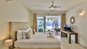 A hotel room with a bed, a television on a side table, and a view of the outdoors. - Waterfront Villa-Amazing View-Pool-Sea-Location#1 (Pointe Pirouette)
