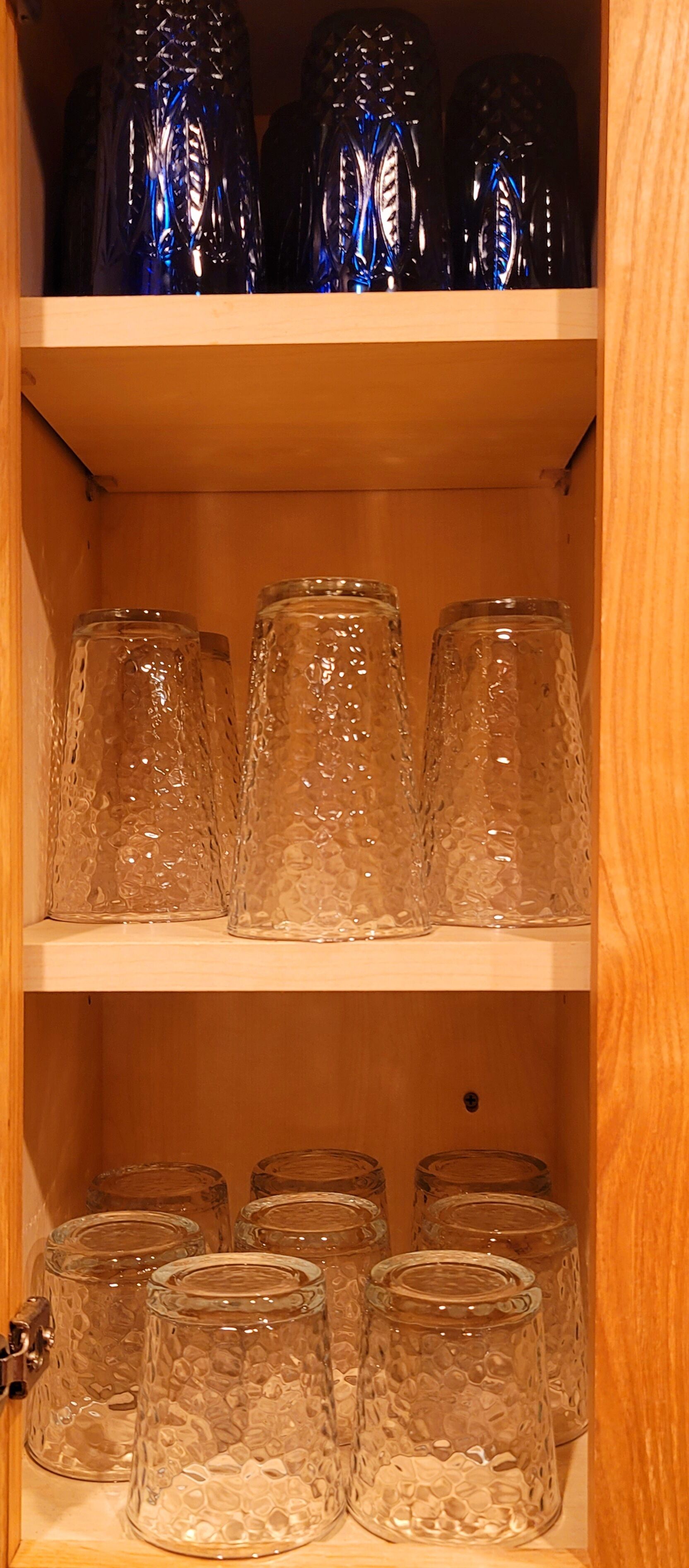 A wooden cabinet with shelves holding various glassware.