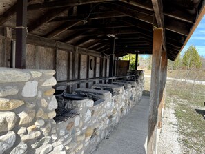 Una construcció de pared de pedra amb una reixa de metall, bigues de fusta i un camí de grava.