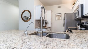 A kitchen with granite countertops, stainless steel appliances, and a modern faucet.