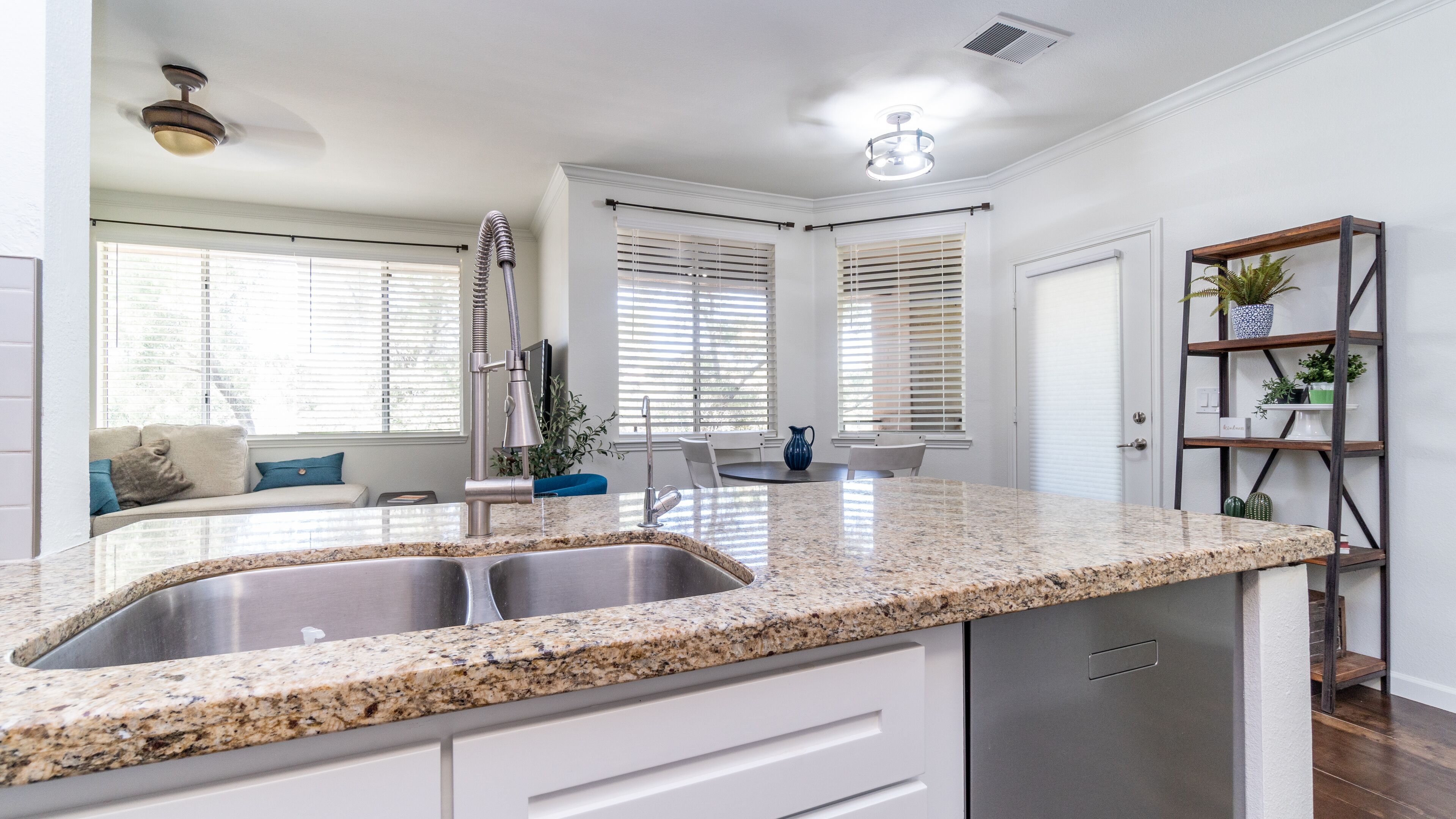 A modern kitchen with granite countertops, stainless steel appliances, and a dining area with a white table and chairs.