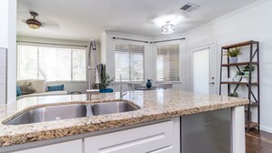 A modern kitchen with granite countertops, stainless steel appliances, and a dining area with a white table and chairs.