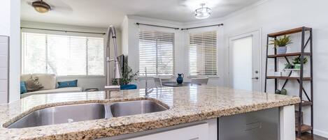A modern kitchen with granite countertops, stainless steel appliances, and a dining area with a white table and chairs.