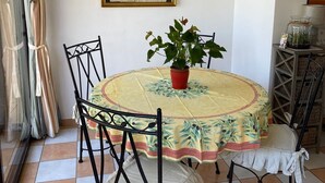 Un coin repas avec une table ronde, des chaises, une plante en pot et un tableau encadré au mur.