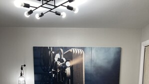 A bedroom with a bed, a nightstand, a wall-mounted light fixture, and a large abstract painting. - Convenient One Bedroom Hancock Condo (Austin)