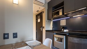 A modern kitchen with stainless steel appliances, a dining table set with plates, cutlery, and glasses. - Charlie Alphaville  (Barueri)