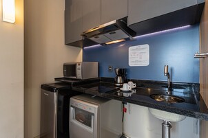 Una cocina compacta equipada con microondas, cafetera y lavavajillas.