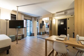 A hotel room with a bed, a desk with a chair, a television, and a mirror. - Charlie Alphaville  (Barueri)