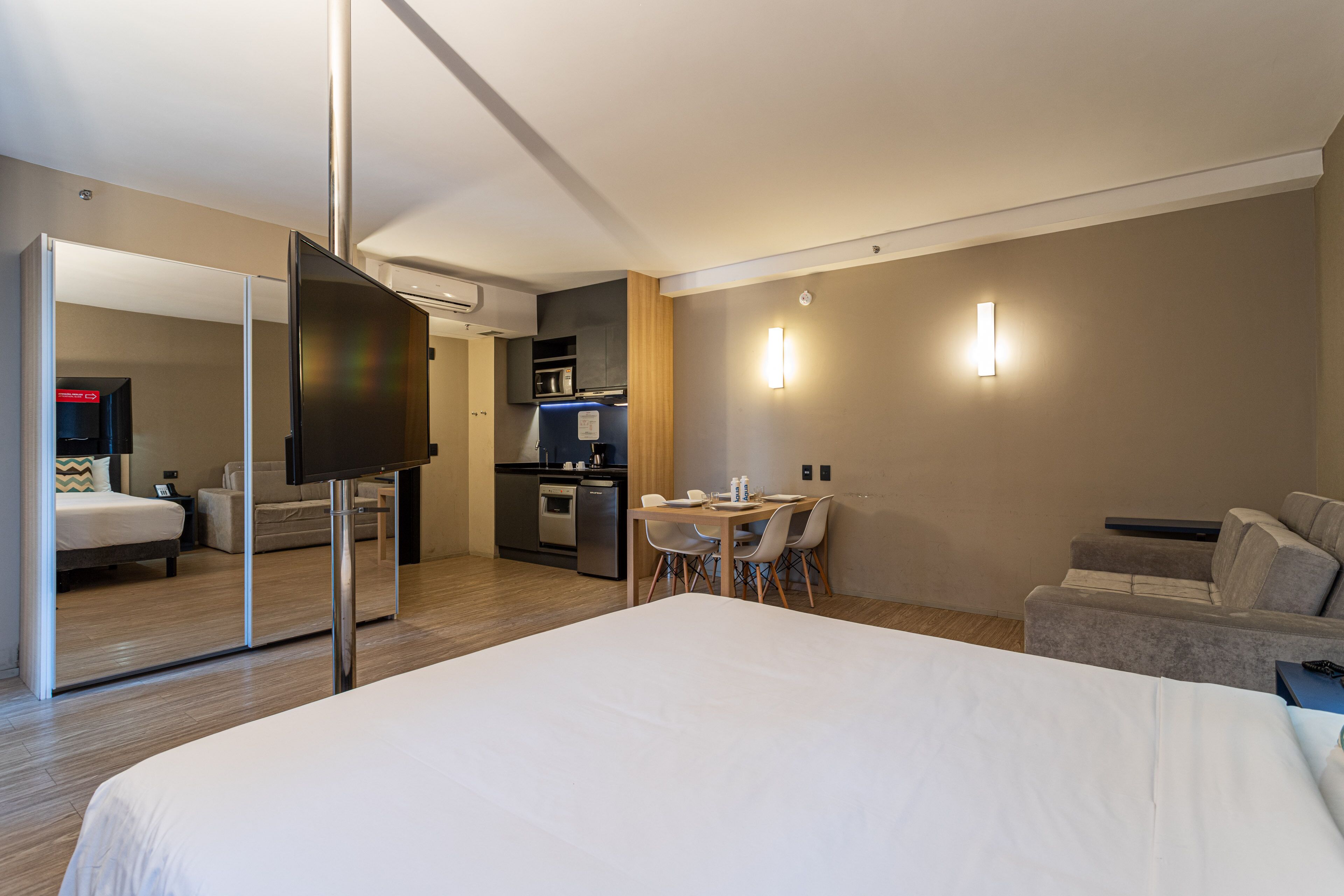 Une chambre d’hôtel comprenant un lit, une télévision, une table à manger avec des chaises, un coin cuisine et un canapé.