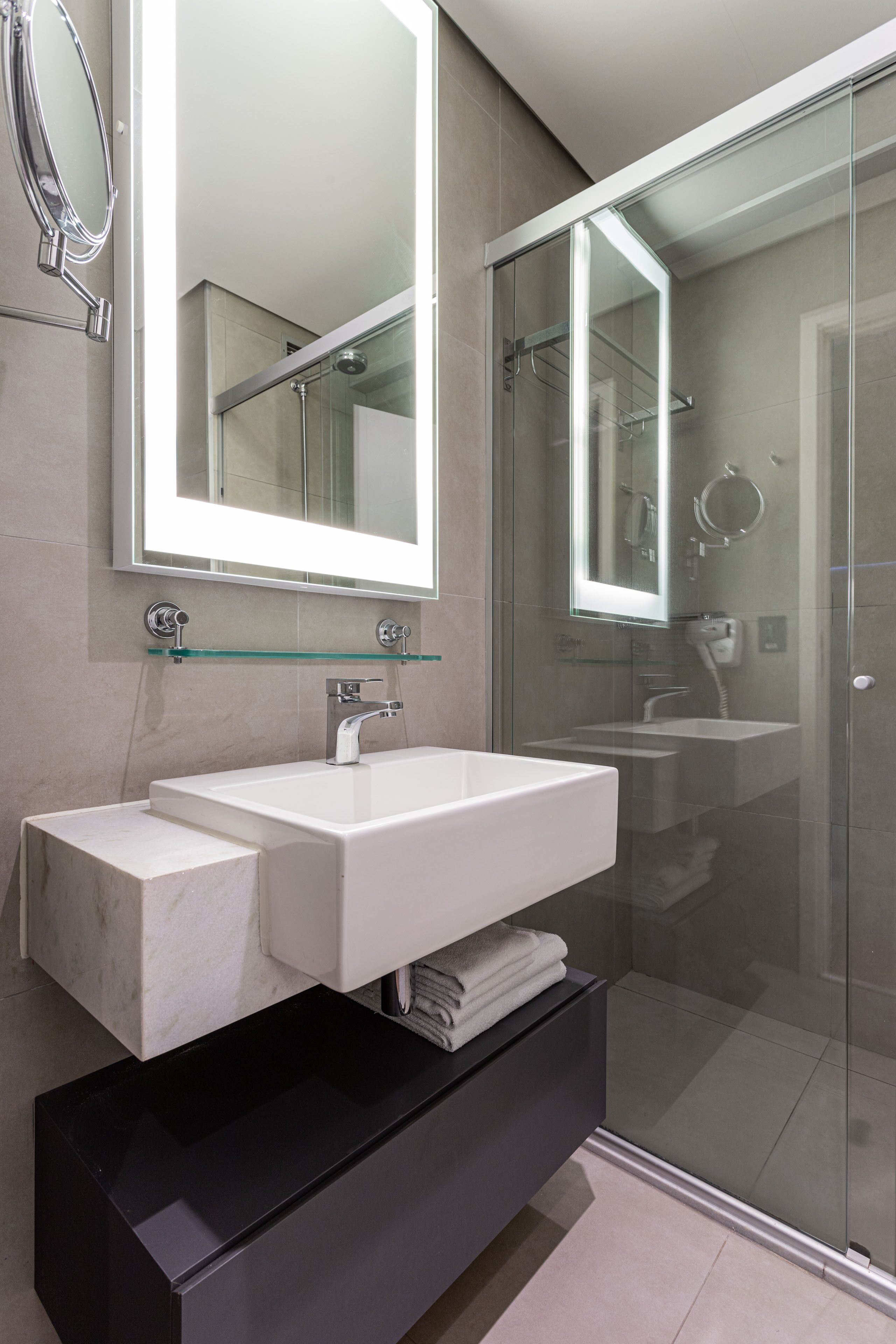 Un baño moderno con un espejo grande, dos lavamanos y una ducha con cerramiento de vidrio.