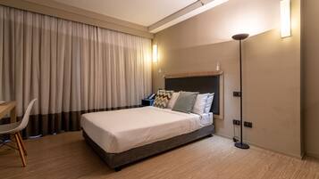 A modern hotel room with a large bed, a desk, and a chair.
