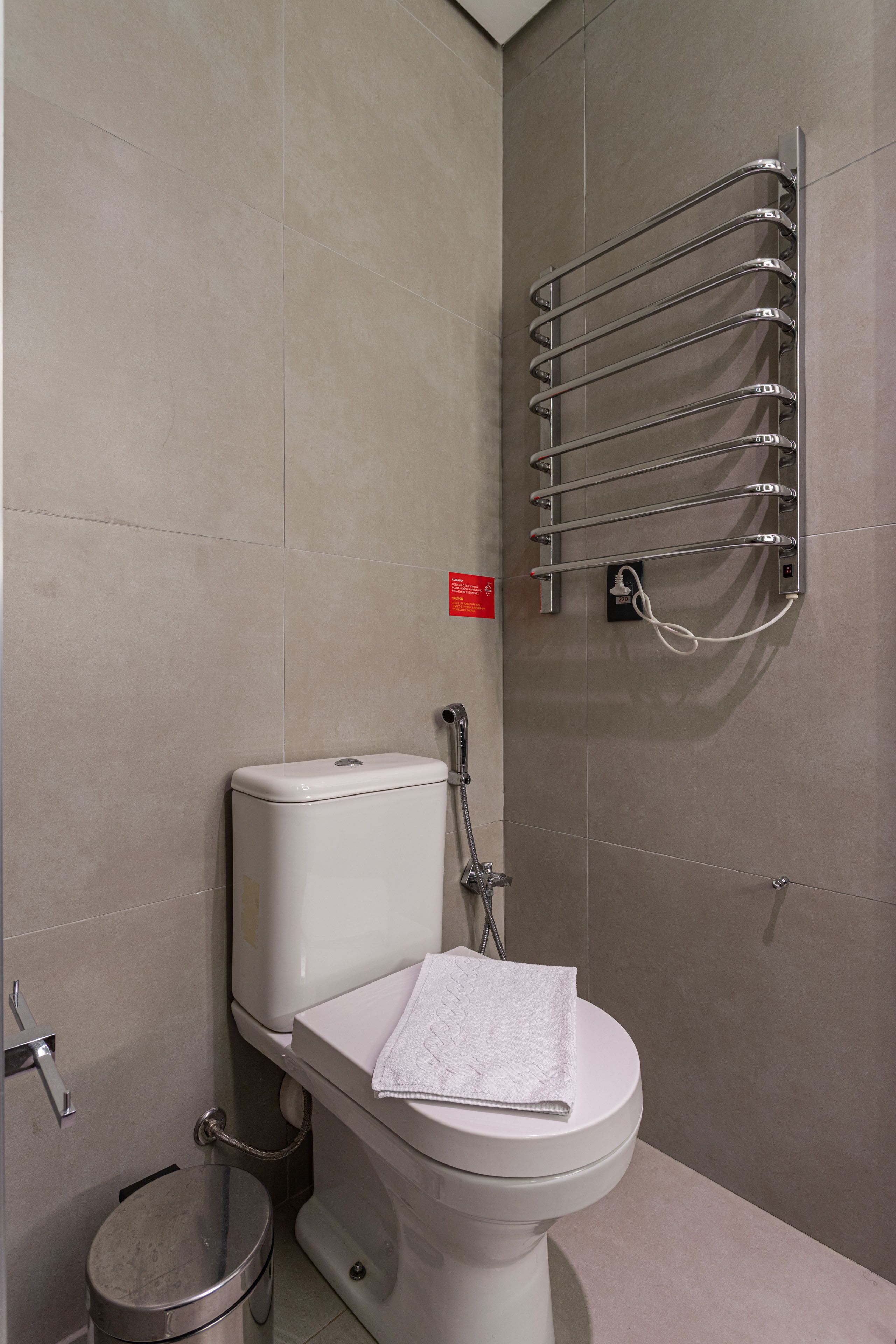 Un baño moderno con inodoro, secamanos y toallero.