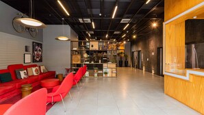 A modern interior with a red sofa, red chairs, a wooden counter, and a bicycle on the wall. - Charlie Alphaville  (Barueri)