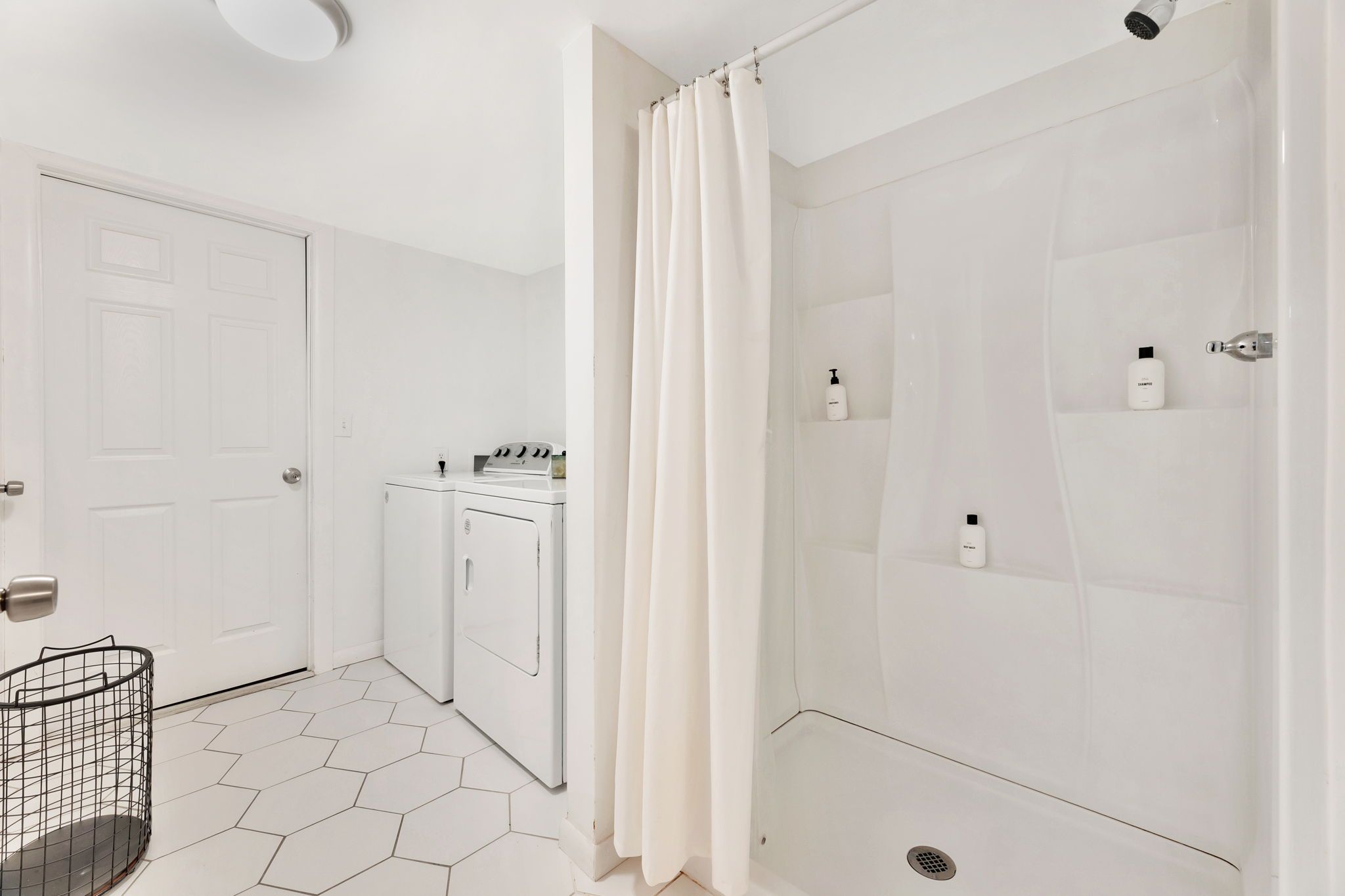 A modern bathroom with a shower, a washing machine, and a toilet.
