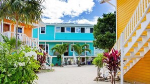 A courtyard with colorful buildings, a staircase, and tropical plants. - Secret Beach Cabanas, Orange Cabana Just Steps from the Water! (San Pedro)