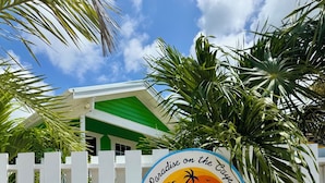 A sign for 'Secret Beach Cabanas' with palm trees and a white fence. - Secret Beach Cabanas, Orange Cabana Just Steps from the Water! (San Pedro)