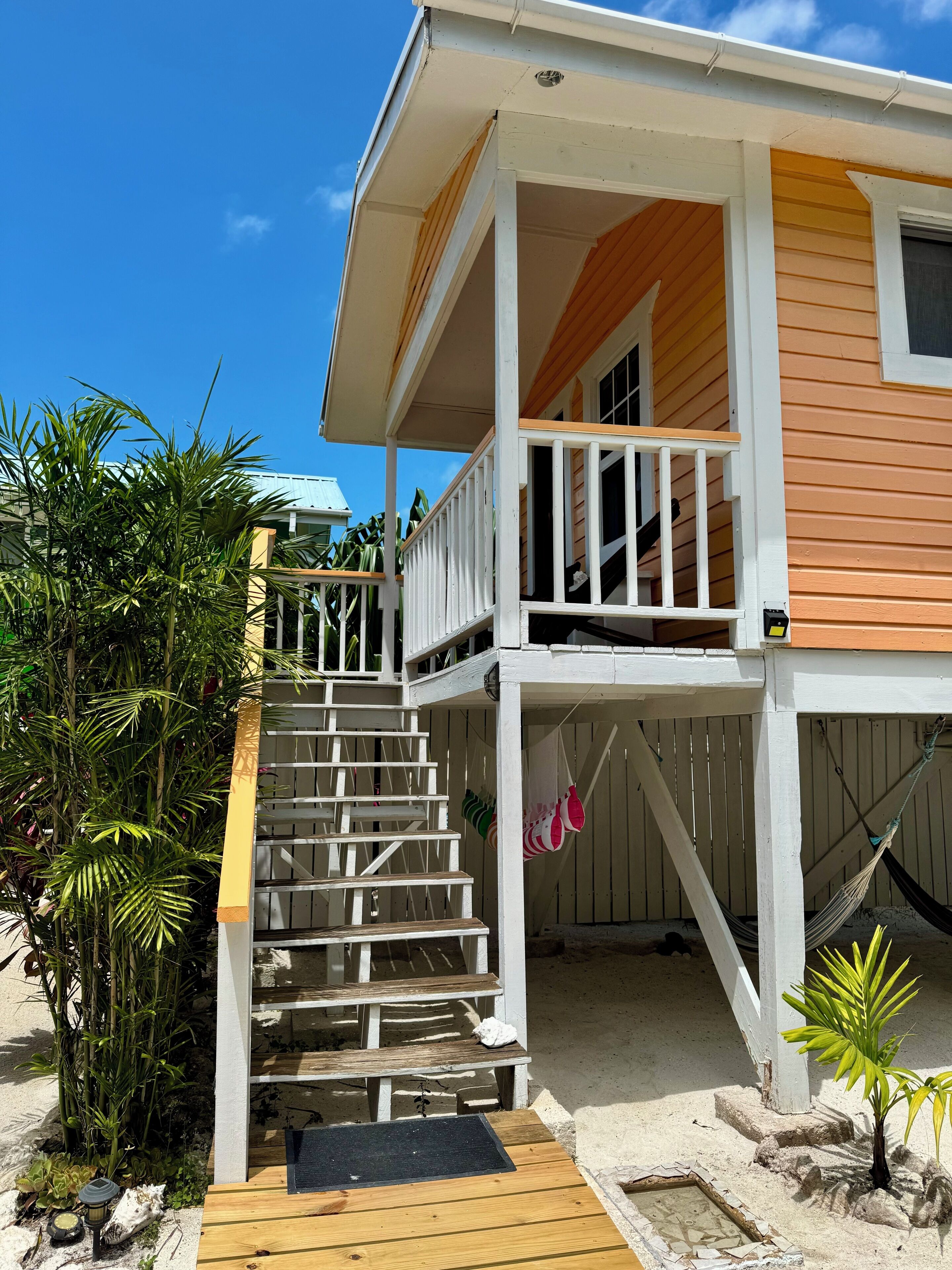 Une maison à deux étages dotée d’une terrasse en bois, d’un balcon et d’un escalier menant à l’étage supérieur.