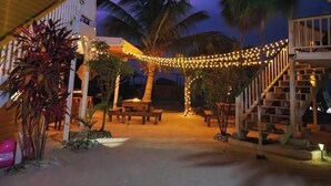 A covered outdoor area with string lights, palm trees, and a staircase. - Secret Beach Cabanas, Orange Cabana Just Steps from the Water! (San Pedro)